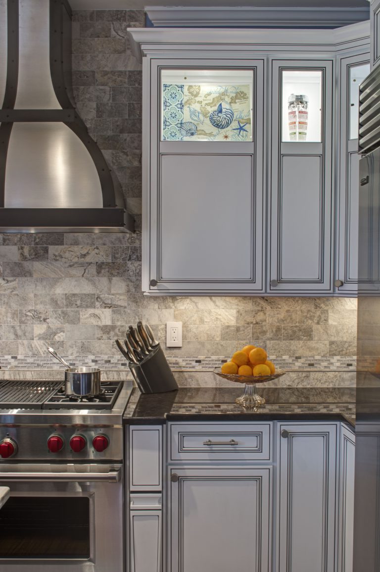 traditional style white cabinetry stainless steel gas range and hood partial glass doors on upper cabinets backsplash tile to ceiling