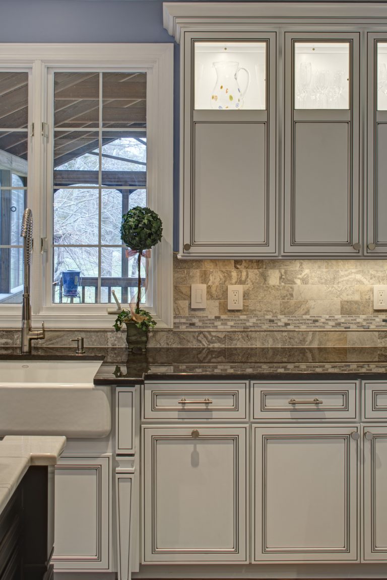 traditional style white wood cabinetry window over porcelain apron sink looks out to screened in porch