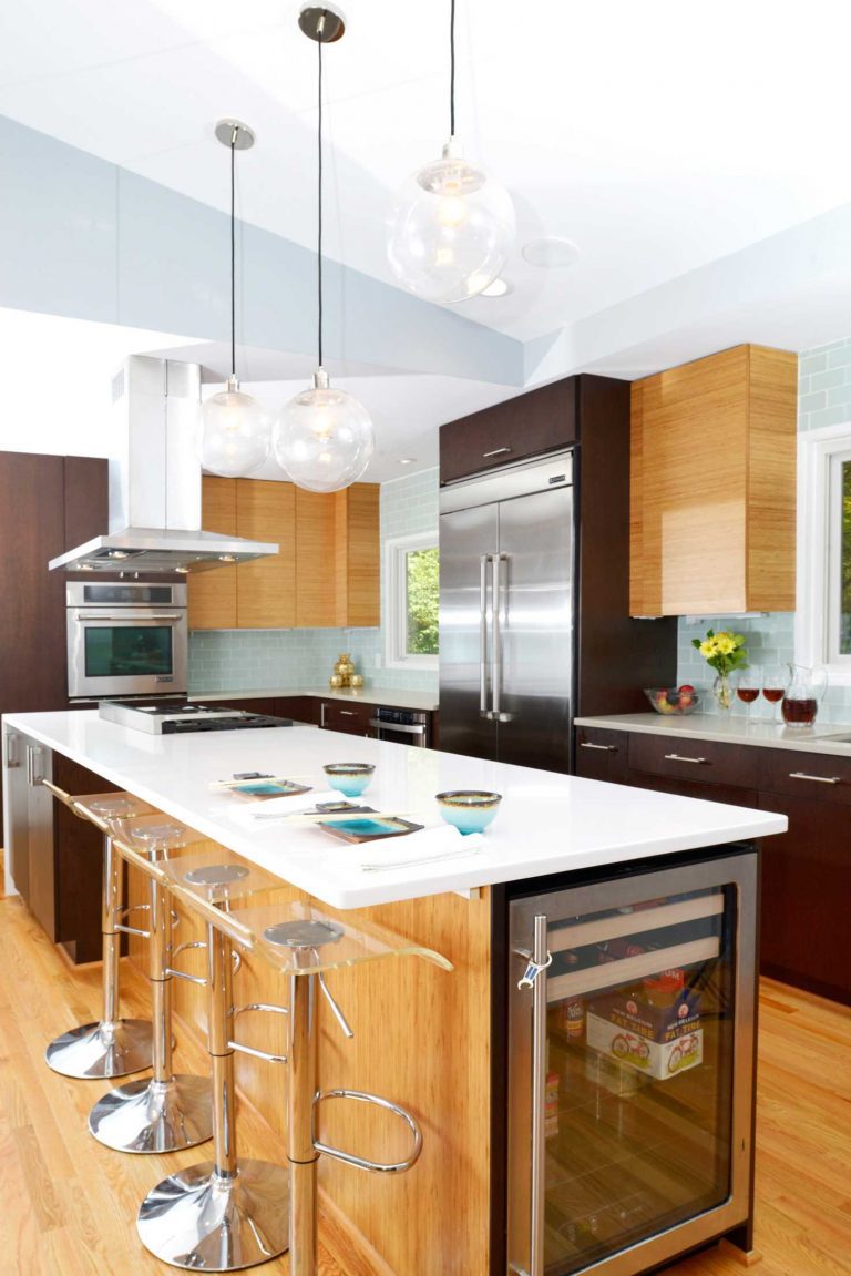 bright modern kitchen with varying wood tones pendant lighting over island vaulted ceiling beverage chiller