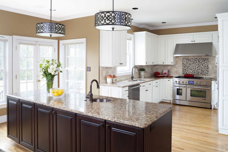 kitchen with mixed dark and white cabinetry warm neutral color palette large windows and glass door pendant lighting