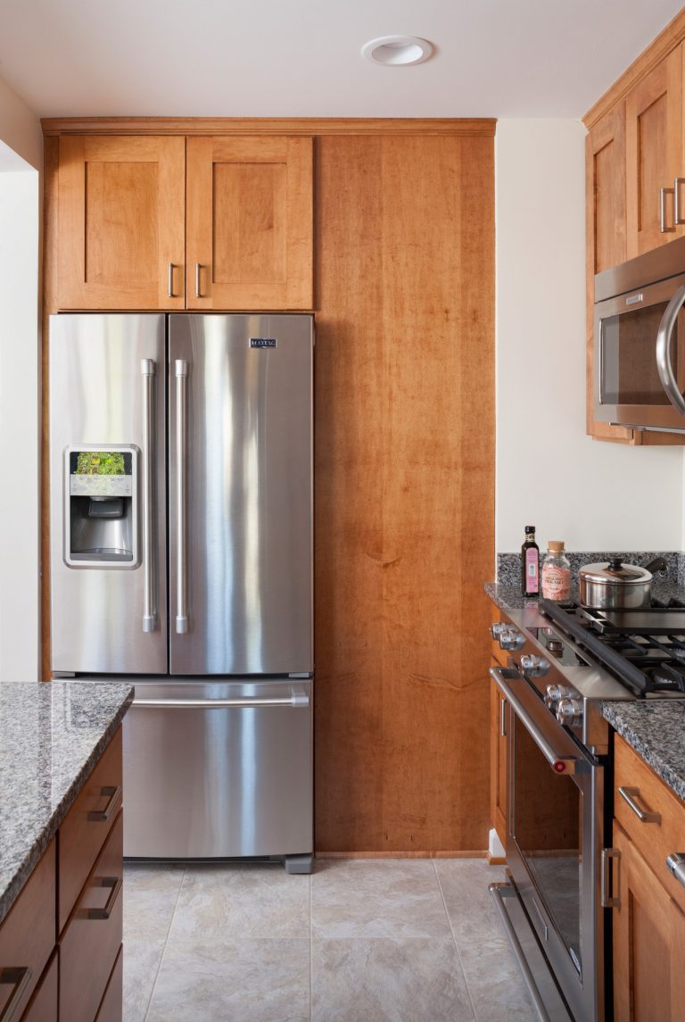 classic craftsman style kitchen with medium stain cabinetry tile floors and stainless steel appliances