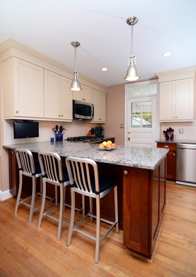 traditional style kitchen dark lower cabinets white upper cabinets peninsula with seating and pendant lighting above gray countertops wood floors