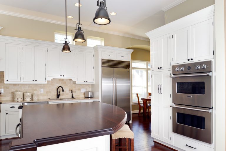 center island white cabinets and dark wood colored countertop flows into dining room windows above upper cabinets