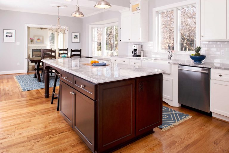 bright white kitchen with dark wood island flows into dining area wood floors large windows recessed and pendant lighting