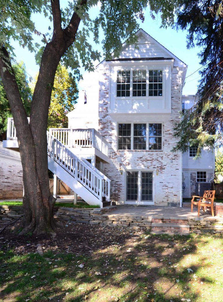 addition on traditional brick virginia home second story deck with stairs to yard ground level sliding doors onto patio