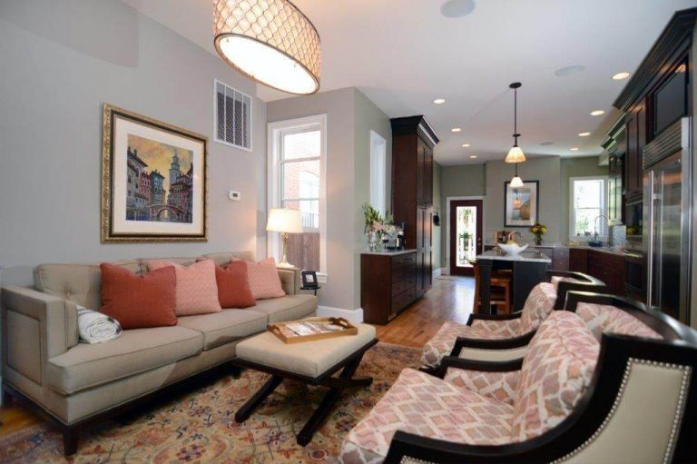 elegant and traditional living area soft blue walls warm color palette hanging overhead lighting opens into kitchen