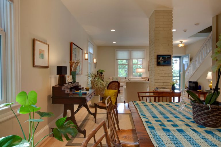 dining area in farmhouse style dc home flows into living area light and warm color palette exposed brick column