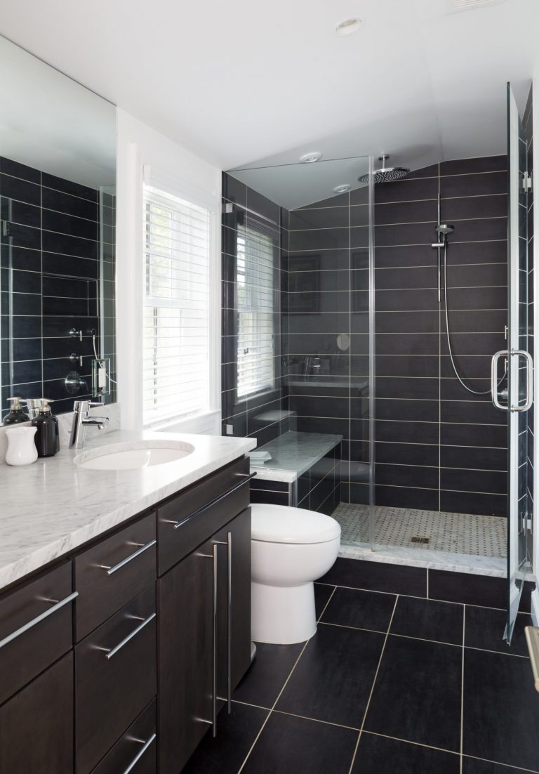 vanity with double sinks separate shower stall with glass door and built in bench black tile