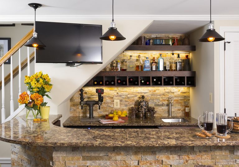 home basement bar stone detail and backsplash warm color tones wall mounted flat screen tv pendant lighting open shelving and storage