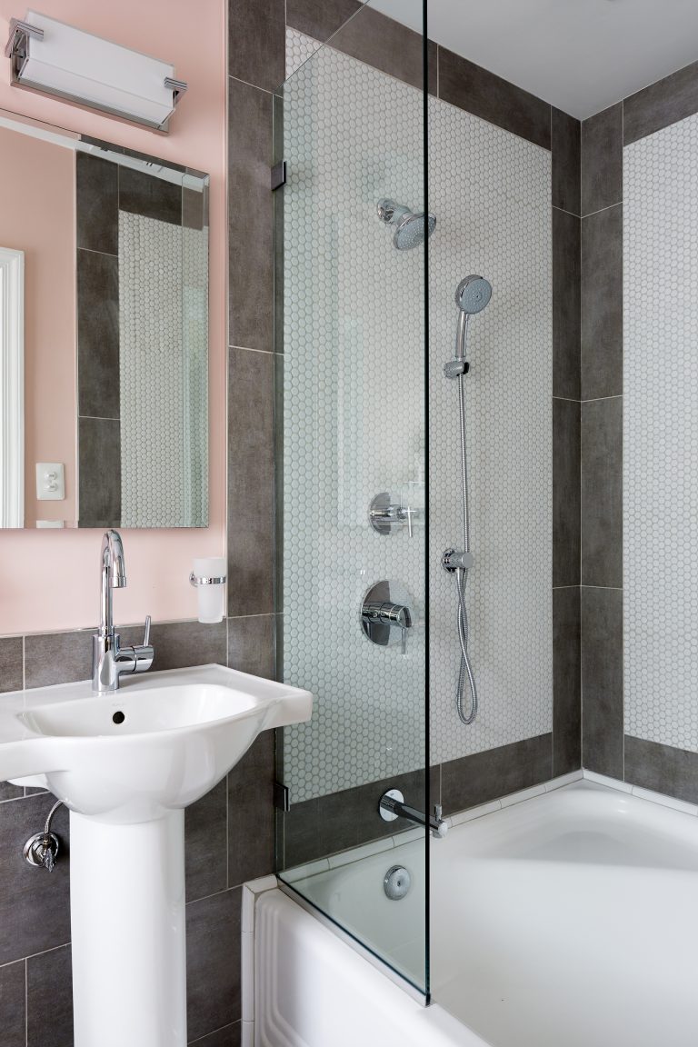 porcelain sink with chrome faucet neutral toned pink walls and gray tile shower and tub with white tile and brown tile border