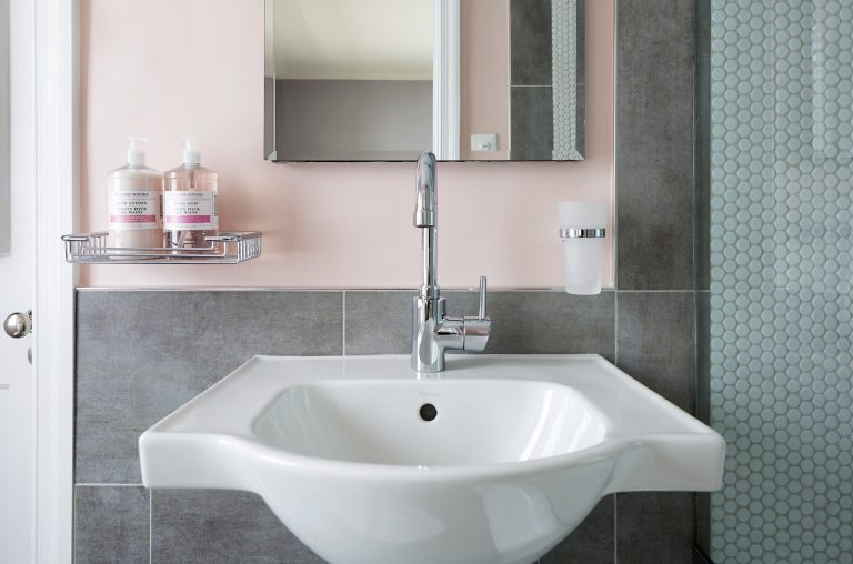 porcelain sink with chrome faucet neutral toned pink walls and gray tile