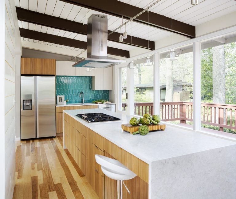 modern kitchen natural wood cabinetry and floors waterfall edge countertops teal tile backsplash beam ceiling