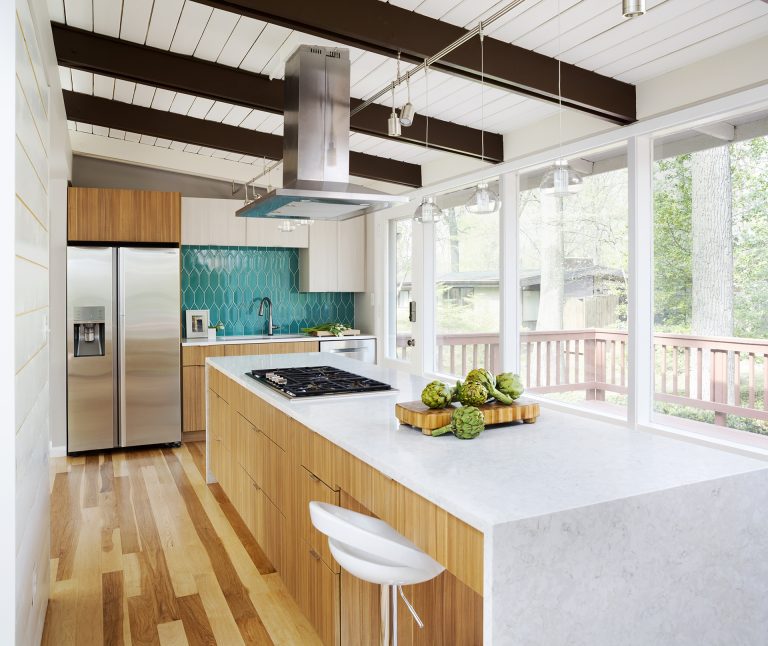 modern kitchen natural wood cabinetry and floors waterfall edge countertops teal tile backsplash beam ceiling