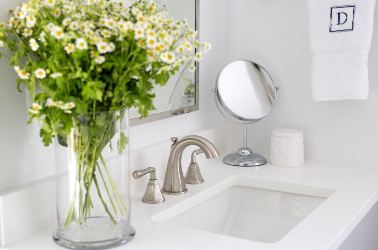 white cabinetry and countertops in bright bathroom with brushed chrome fixture