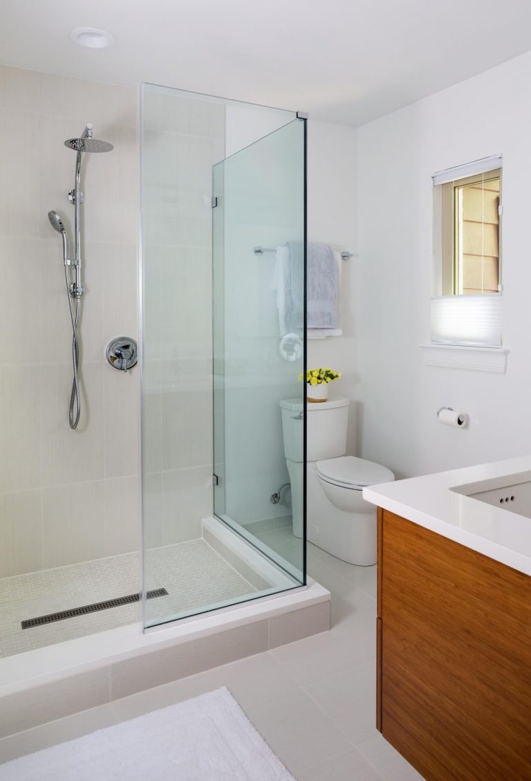 white bathroom shower stall with glass wall wood toned vanity