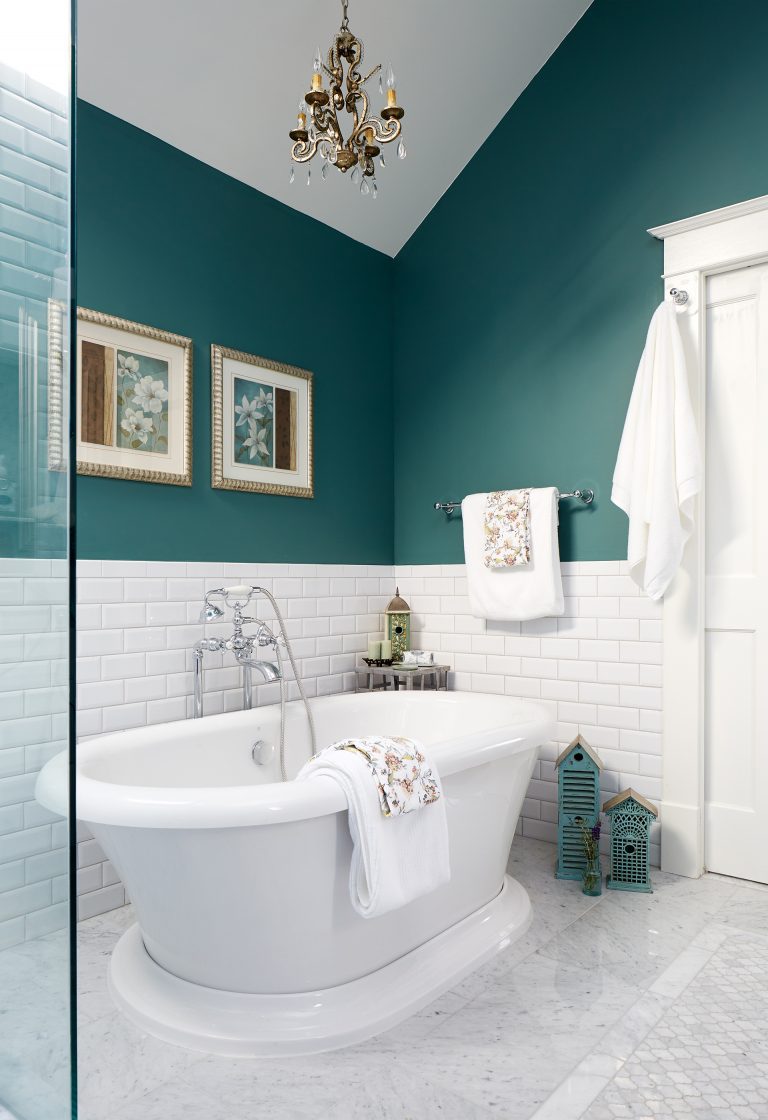 freestanding tub half wall subway tile wainscot teal walls gold chandelier