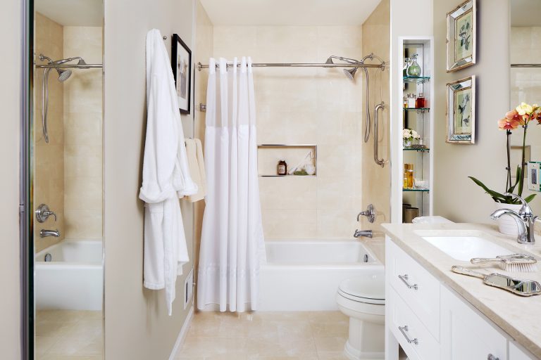 renovated bathroom beige and cream color palette vanity with white cabinetry storage nook in shower