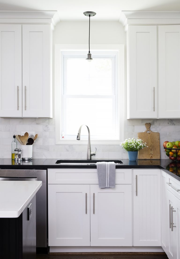 kitchen sink with brushed chrome fixture in front of window with pendant light above