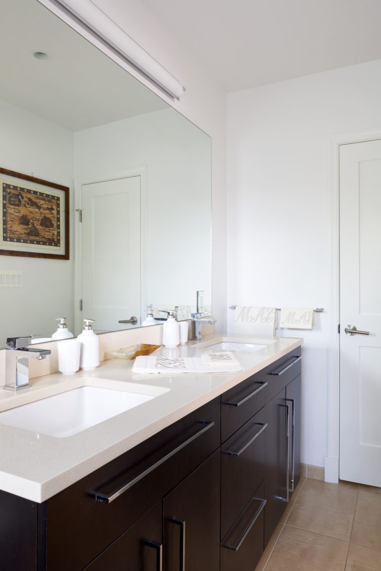 bright bathroom with double sink vanity and mirrored wall