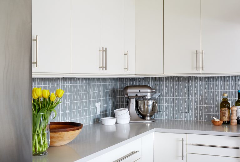 kitchen with white cabinetry gray countertops geometric tile backsplash