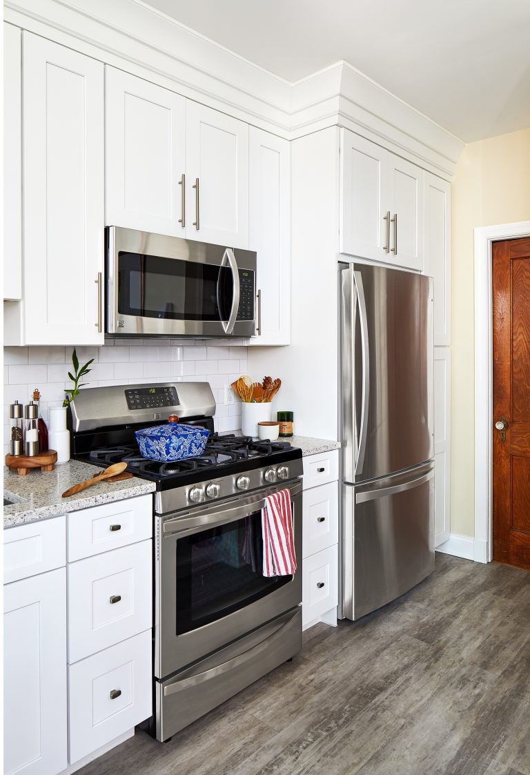 kitchen with wood floors white cabinetry and stainless steel appliances