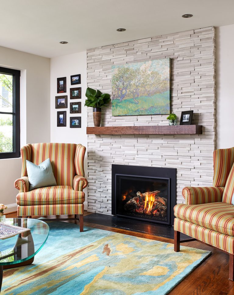 living room with stone fireplace and wood mantle wood floors and windows with black pane