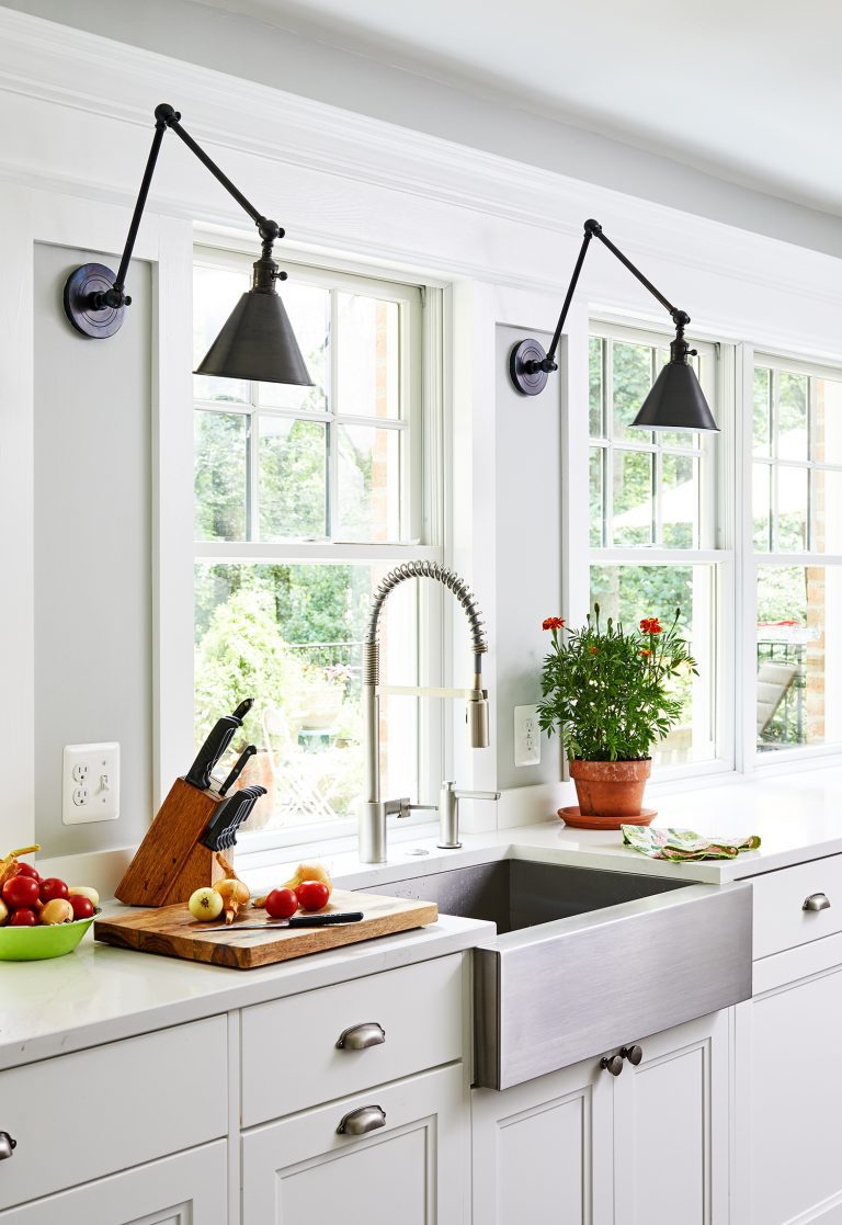 two black pendant lights over kitchen counter and large farmhouse sink
