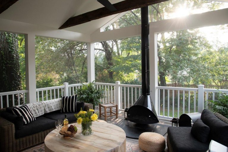 patio black fireplace in the middle of the room, round wooden table and black couches