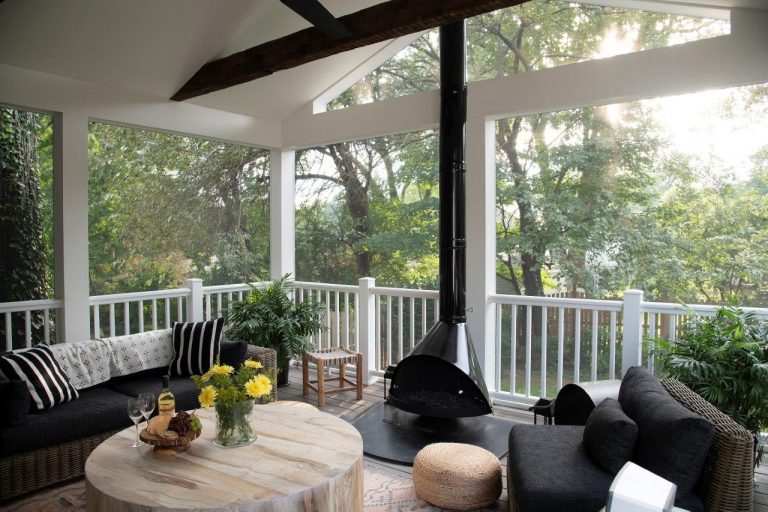 interior design outdoor patio with round wood table and black fire place, black cushion chairs screen porch