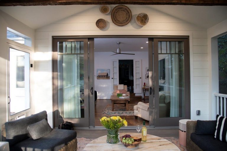 large patio with rusty wood beam, outdoor ceiling fan, wooden round table, black fireplace