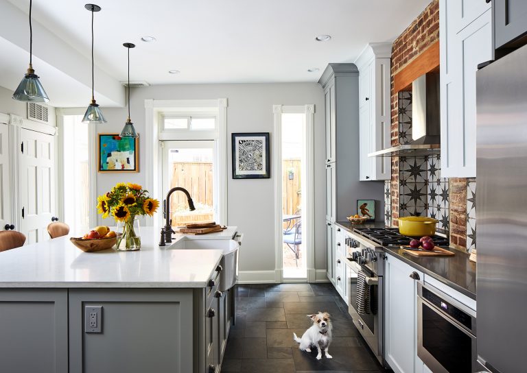 Island with farmhouse sink white cabinets with black knobs and back door leaving to the porch