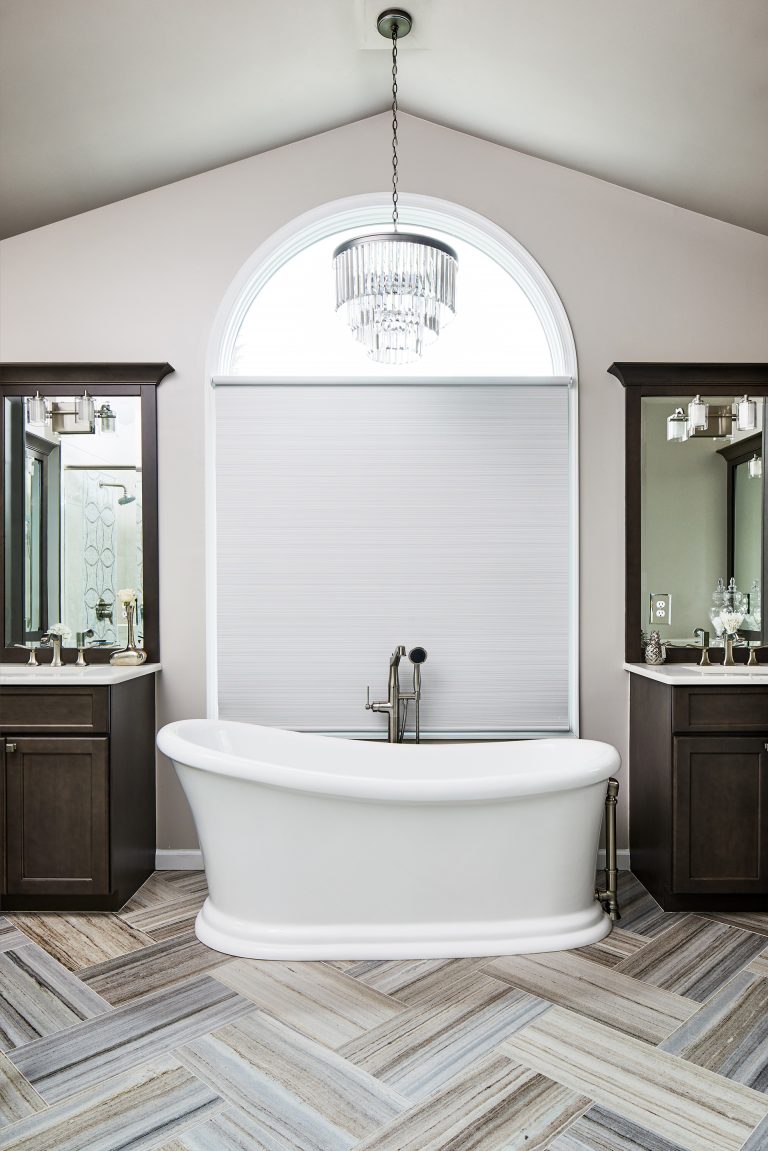 master bath with marble floor and stand along tub in between his and her vanity