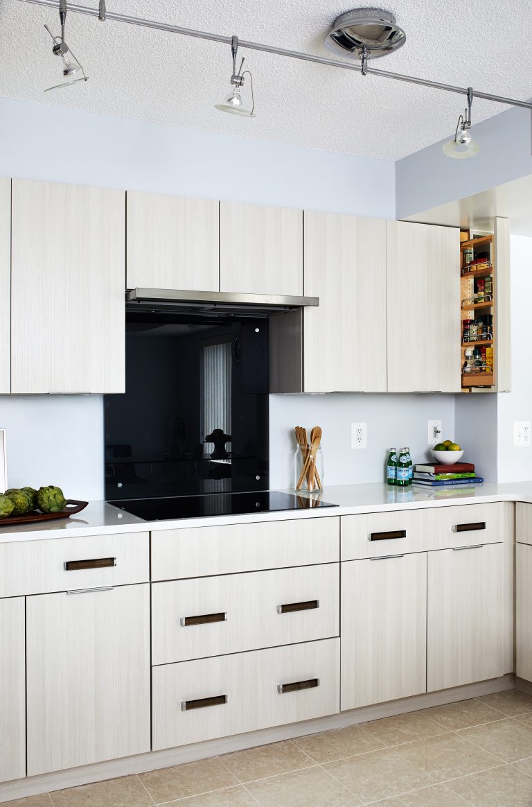 White cabinets doors, black back splash, black stovetop with kitchen track lighting