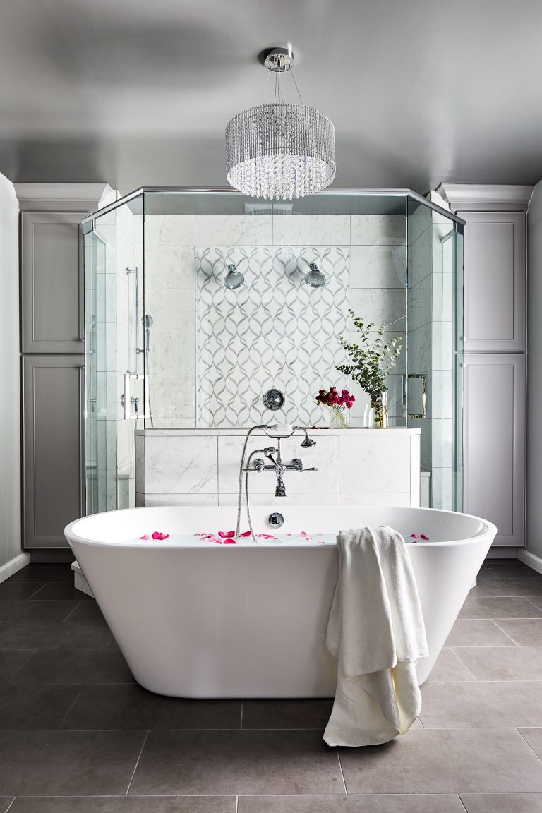 huge crystal chandelier above the white oval bath tub