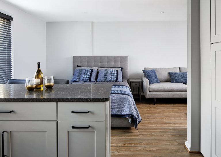 small kitchen island with grey marble counter top and black pull handles