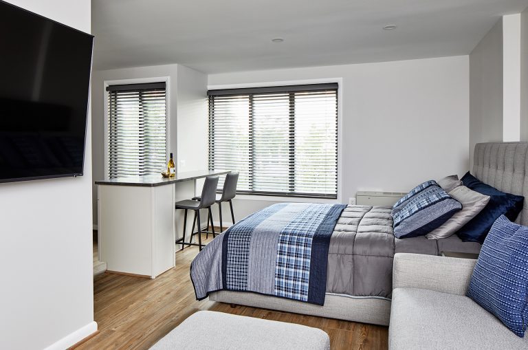 small two seat kitchen island near the front windows, facing just one room with no walls to separate the bedroom from the living room